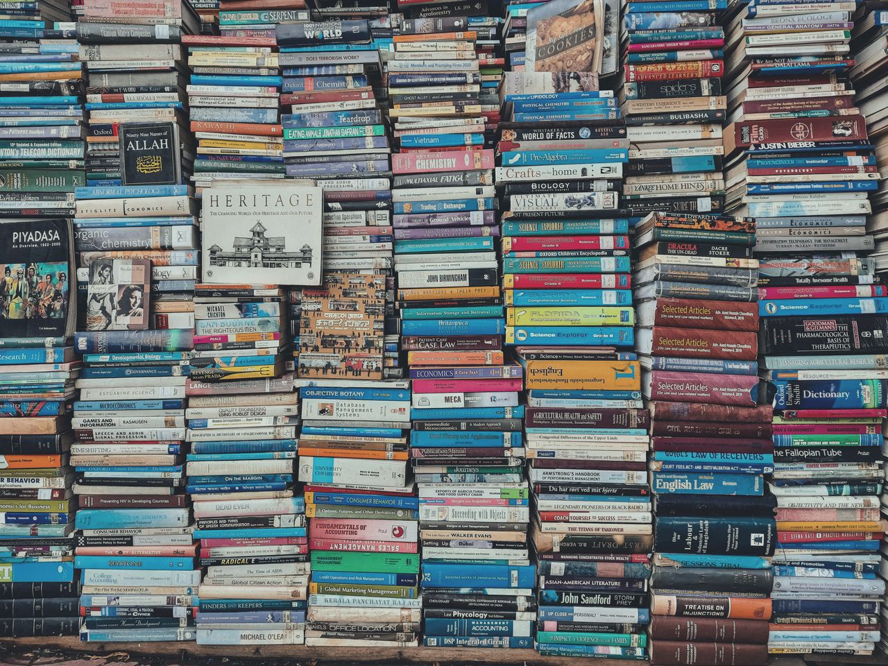 A vibrant collection of stacked books creating a visually arresting pattern in a Dhaka bookstore.